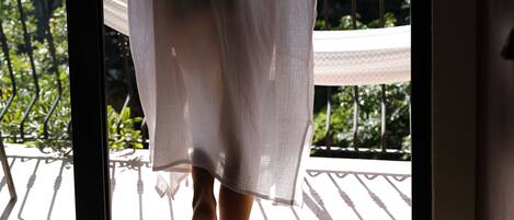A person in a white robe stepping onto a balcony.