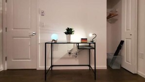 Una habitación con una puerta blanca, un escritorio de metal negro con una planta, un globo terráqueo y un libro.