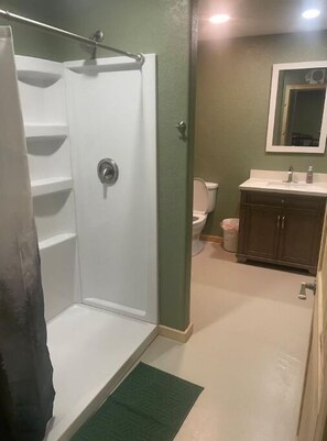 A bathroom with a shower, toilet, and sink. - Puddle Duck Lodge (Corning)