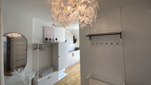 Ein moderner, minimalistischer Raum mit einem großen Spiegel, weißen Schränken und einer außergewöhnlichen Deckenleuchte.