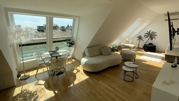 Eine moderne Loftswohnung mit großem Dachfenster, Holzboden, einem runden Esstisch und einer gemütlichen Sitzecke.