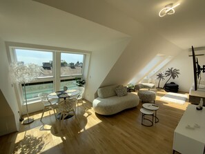 Eine moderne Loftswohnung mit großem Dachfenster, Holzboden, einem runden Esstisch und einer gemütlichen Sitzecke.