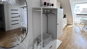 Ein modernes, minimalistisches Zimmer mit einem großen Spiegel, einem weißen Schrank mit Kleiderstange und Holzboden.