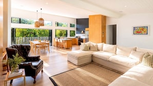 Una sala moderna con un sofá modular, un comedor y una cocina.