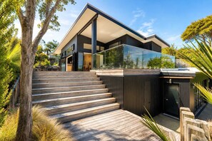 Une maison moderne dotée d’une terrasse en bois qui mène à un patio entièrement vitré.