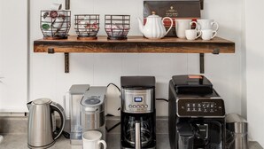 Een keuken met twee houten planken met keukengerei, een koffiezetapparaat en een waterkoker.