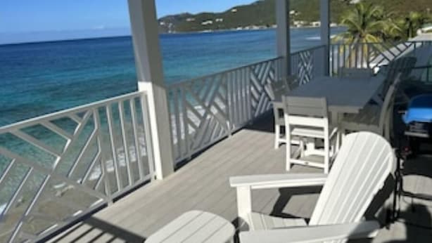 Un espace extérieur abrité, aménagé avec des chaises blanches et une table, et offrant une vue sur l’océan.