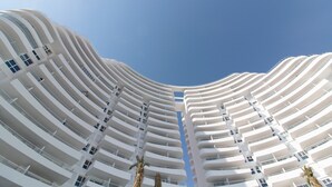 A high-rise hotel with a curved facade, multiple balconies, and a clear sky.
