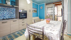 Una cocina con salpicadero de azulejos, una estufa y un comedor con una mesa dispuesta para dos.
