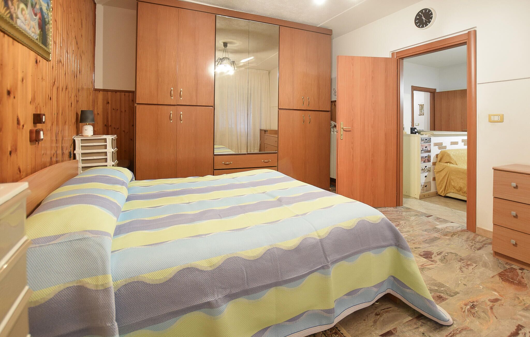 Ein Schlafzimmer mit einem Bett, einem Holzschrank und einem Spiegel.