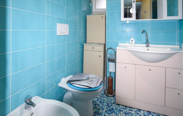 Une salle de bain comprenant des toilettes, un bidet, un lavabo et un meuble de rangement.