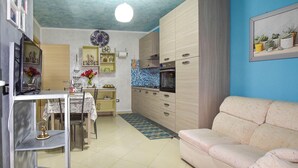 Un espacio habitable compacto con kitchenette, comedor y zona de estar.