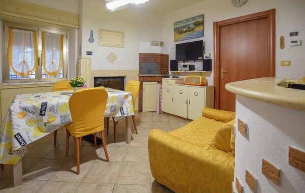 A compact kitchen with a built-in oven and microwave, a dining table with yellow chairs, and a small seating area with a yellow armchair. - 4 bedroom lovely apartment in Roccaspinalveti (Roccaspinalveti)