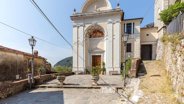 Un edificio histórico con un arco central, una cúpula y una estatua sobre la entrada.