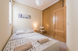 A bedroom with a bed, a nightstand, a chair, a wooden wardrobe, and a wall-mounted picture. - Sunny Loft Historic District - Sol (Madrid)