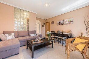 A living room with a sofa, coffee table, dining table, chairs, and a wicker chair. - Sunny Loft Historic District - Sol (Madrid)