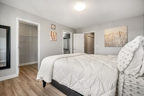 A bedroom with a large bed, a closet, and a door leading to another room. - New Edmonton House 10 mins to Airport, Super close to best places in Edmonton (Edmonton)