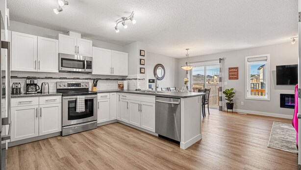 A modern kitchen with white cabinets, stainless steel appliances, and a wooden floor. - New Edmonton House 10 mins to Airport, Super close to best places in Edmonton (Edmonton)