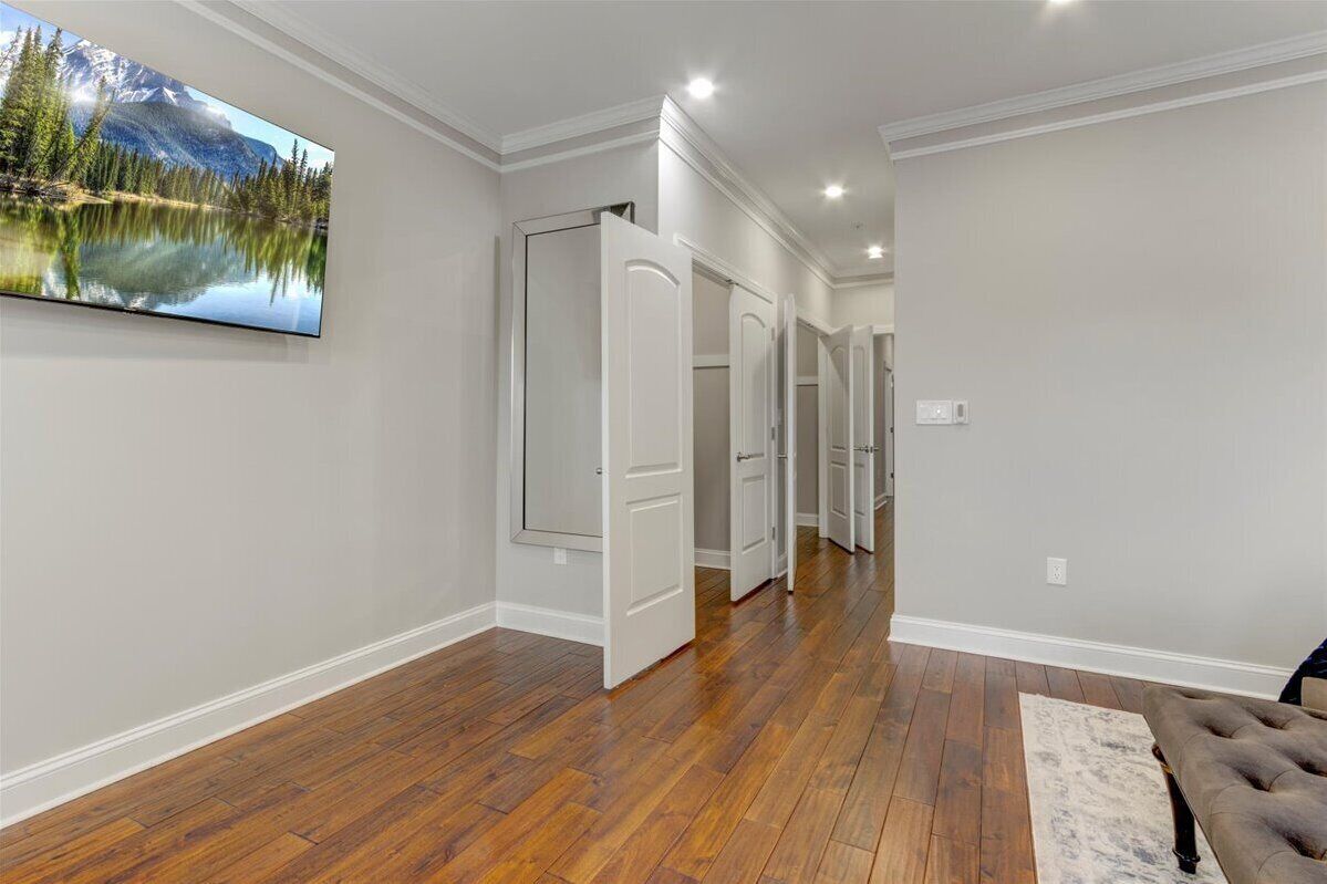 A hallway with wooden flooring, white walls, and a large landscape painting.