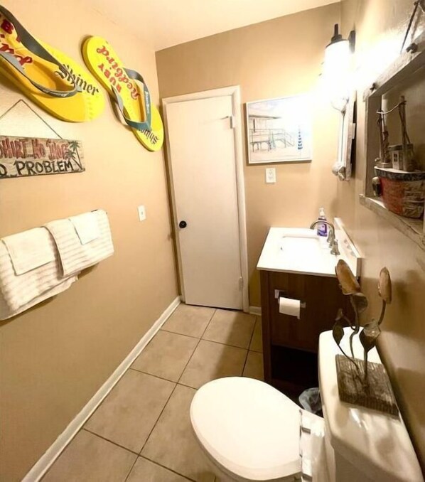 A bathroom with a toilet, sink, and towel rack. - Amazing Palm Beach RETRO Hot Tub Pool Arcade Tropical Home (West Palm Beach)