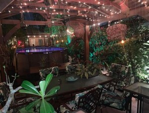 An indoor pool area with a wooden deck, surrounded by tropical plants and chairs. - Amazing Palm Beach RETRO Hot Tub Pool Arcade Tropical Home (West Palm Beach)