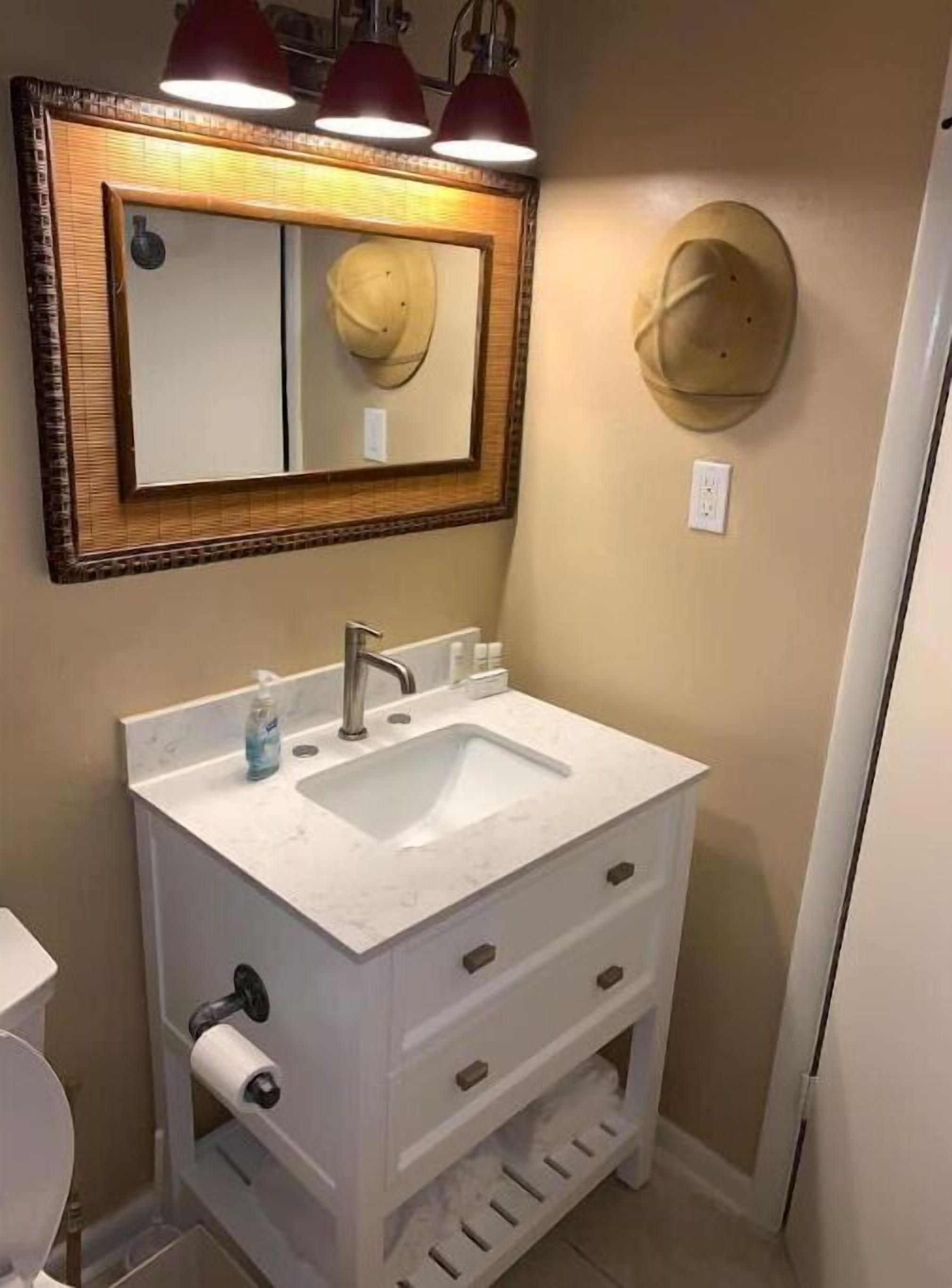 Une salle de bain avec un meuble-lavabo blanc, un miroir avec un cadre en bois, un porte-serviettes et des toilettes.