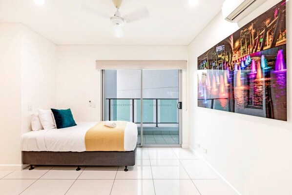 A hotel room with a bed, a balcony, and a cityscape view.