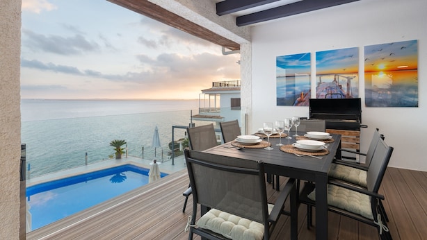 A balcony with a pool, dining table, chairs, and a TV. - VILLA PRESIDENTE (Alcúdia)