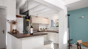 A modern kitchen with a central island, white cabinetry, and a checkered floor. - Villa Estranys (Alcúdia)