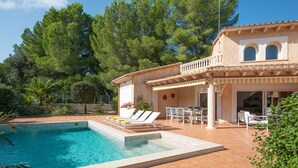 A swimming pool with a tiled deck, lounge chairs, and a patio area with tables and chairs. - Villa Estranys (Alcúdia)