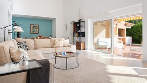 A spacious living room with a beige sofa, a coffee table, and a bookshelf. - Villa Estranys (Alcúdia)