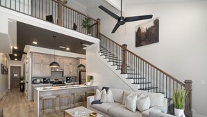 A spacious living area with a large sofa, a coffee table, and a kitchen area with a central island and bar stools. - Buck Creek BNB (Helena)