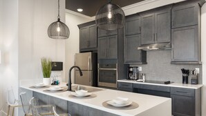 A modern kitchen with a central island, stainless steel appliances, and dark cabinetry. - Buck Creek BNB (Helena)