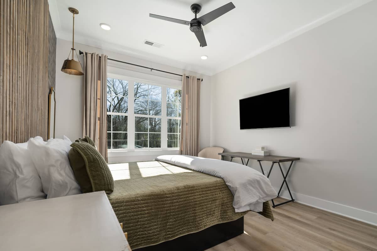 Une chambre à coucher moderne avec un lit, un bureau et un téléviseur.
