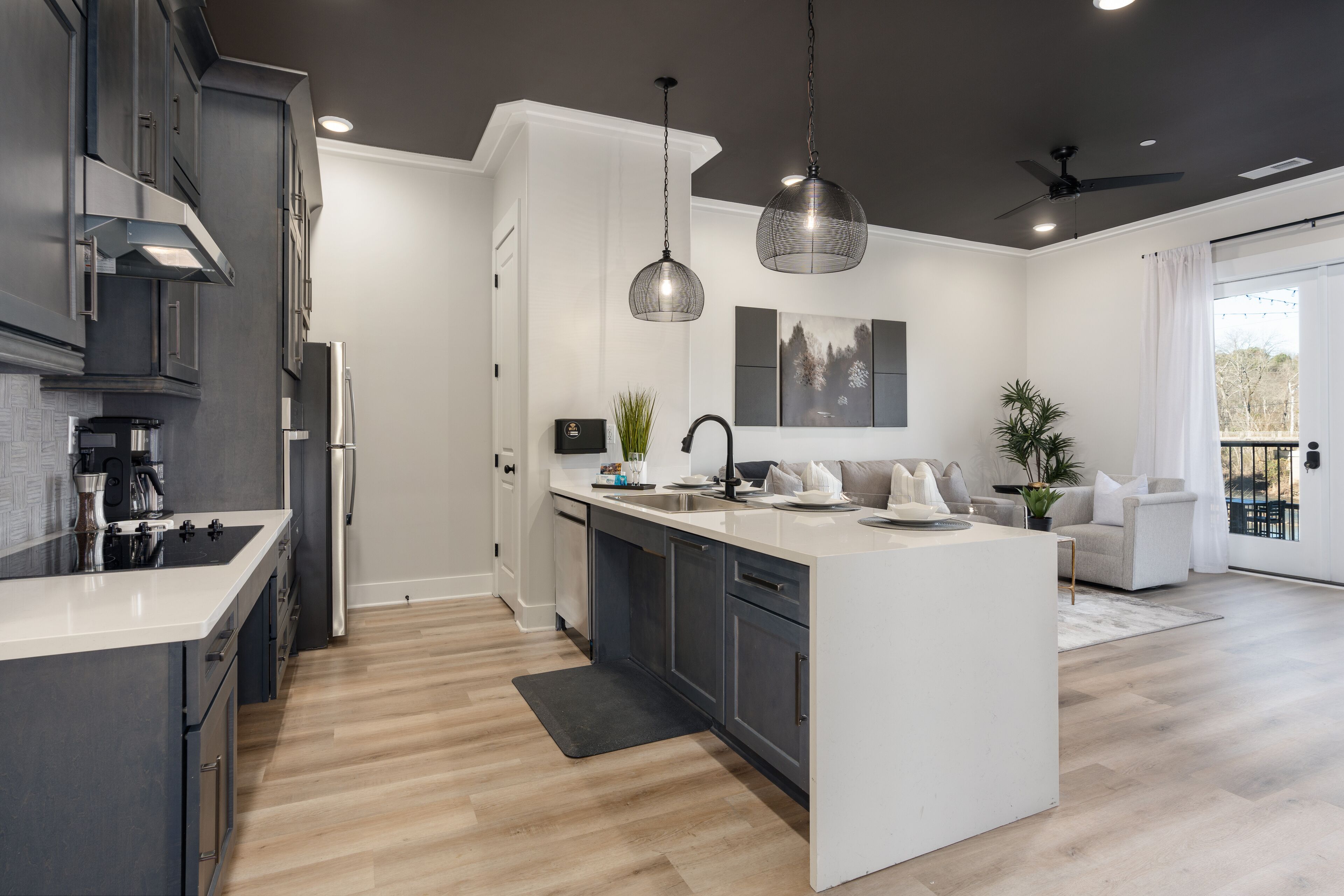 A modern kitchen with a central island, dark cabinetry, and pendant lighting.