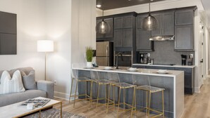 A modern kitchen with a central island, bar stools, and pendant lighting. - Buck Creek BNB (Helena)