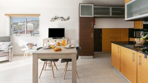 Une cuisine moderne avec un coin repas, un téléviseur à écran plat et une vue sur l’extérieur.