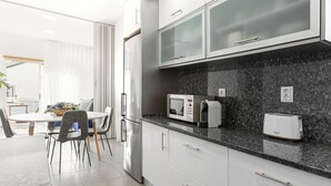 Une cuisine moderne avec des meubles blancs, un plan de travail en granit, un four à micro-ondes, un grille-pain et un réfrigérateur.