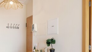 Un pasillo moderno con una consola de madera, una lámpara colgante, una planta en maceta y un florero con plantas secas.