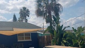 Una piscina cristallina azzurra con lettini, un muro in pietra e vegetazione tropicale.