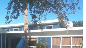 Un edificio moderno a due piani con tetto piatto, ampie finestre e un vialetto in pietra che conduce all'ingresso.