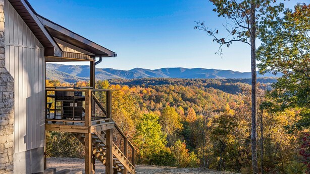 A wooden deck with a staircase leading to a covered area, overlooking a forested valley with autumn foliage and distant mountains. - Eagle Ridge - Ridge Road Scenic Cabins - Brimstone Recreation and Big South Fork (Robbins)