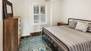 A bedroom with a bed, wooden dresser, window with blinds, and a ceiling fan. - Eagle Ridge - Ridge Road Scenic Cabins - Brimstone Recreation and Big South Fork (Robbins)