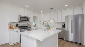 A modern kitchen with white cabinetry, a central island, stainless steel appliances, and a marble countertop. -  Stepping Stones  away from the Colorado River. (Bullhead City)
