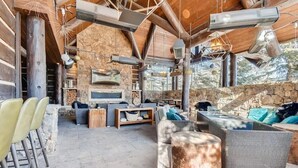 Un espacio de estar al aire libre rústico con paredes de piedra, vigas de madera y chimenea de piedra.