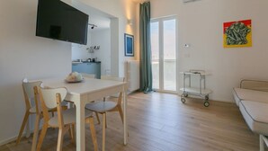A modern apartment with a dining area, kitchenette, and a balcony.