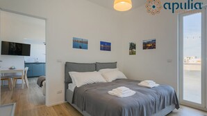 A modern bedroom with a bed, a desk, and a TV.