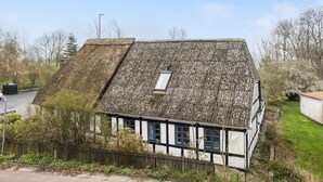 Une maison traditionnelle à colombages, dotée d’un toit à forte pente et d’une petite lucarne.