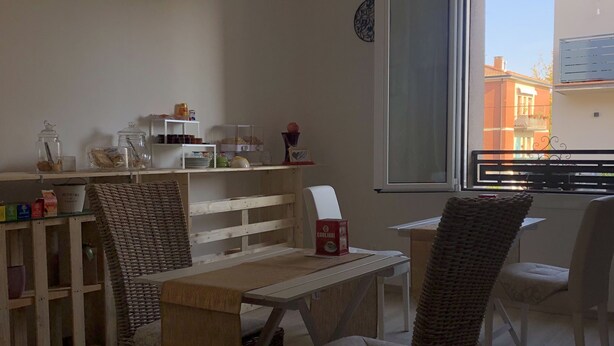 A dining area with wicker chairs, a wooden table, and a view of the outside through a large window. - 2 Bedroom Bed & breakfast in Modena (Modena)