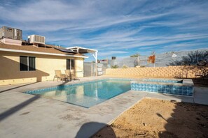 A residential backyard with a swimming pool, a covered patio area, and a brick wall. - Phoenix Desert Paradise | Pool & Jacuzzi | Grill!, Phoenix Desert Paradise | Pool & Jacuzzi | Grill! (Joshua Tree)